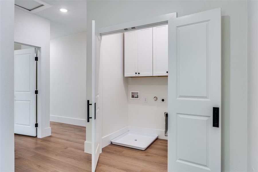 Washroom featuring washer hookup, cabinet space, light wood-style flooring, recessed lighting, and gas dryer hookup Washroom featuring washer hookup, cabinet space, light wood-style flooring, recessed lighting, and gas dryer hookup
