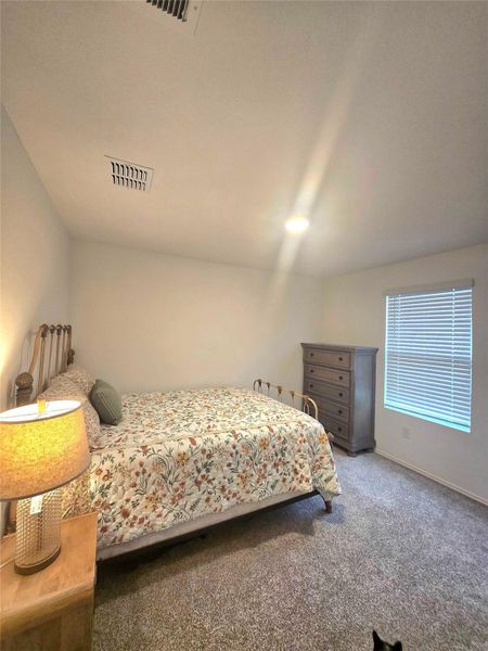 Well-lit room with textured carpeting, a single window with blinds, and white walls