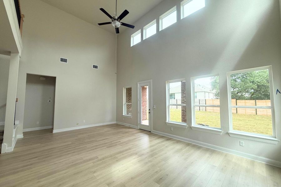 Vaulted ceiling with a ceiling fan, light wood-finish flooring, multiple transom windows, and a glass-paneled door leading to the backyard Vaulted ceiling with a ceiling fan, light wood-finish flooring, multiple transom windows, and a glass-paneled door leading to the backyard