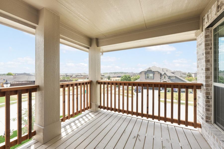 Covered second-floor balcony with wood railing and neighborhood street view