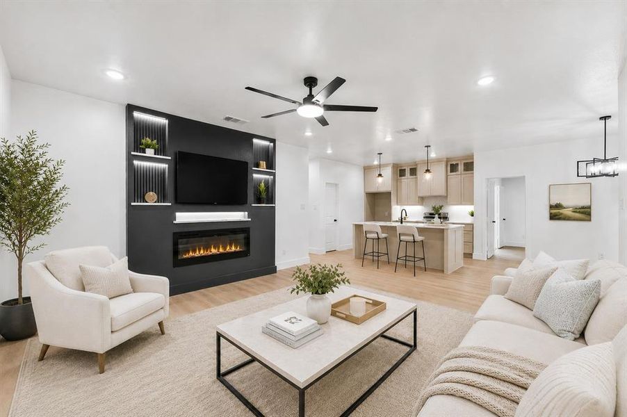 Open-concept living space featuring a built-in media center with an electric fireplace, recessed lighting, and wood-finish flooring Open-concept living space featuring a built-in media center with an electric fireplace, recessed lighting, and wood-finish flooring