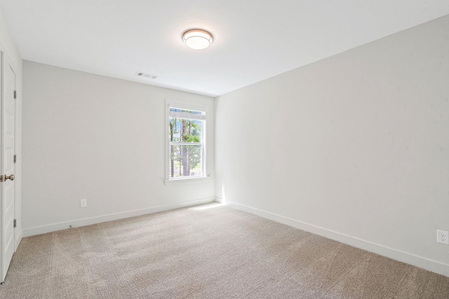 Bright room featuring light-toned carpeting, neutral wall paint, and a white trim package Bright room featuring light-toned carpeting, neutral wall paint, and a white trim package