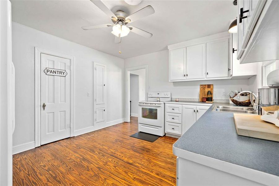 Kitchen featuring white appliances, white cabinetry, dark wood-style flooring, and a ceiling fan Kitchen featuring white appliances, white cabinetry, dark wood-style flooring, and a ceiling fan
