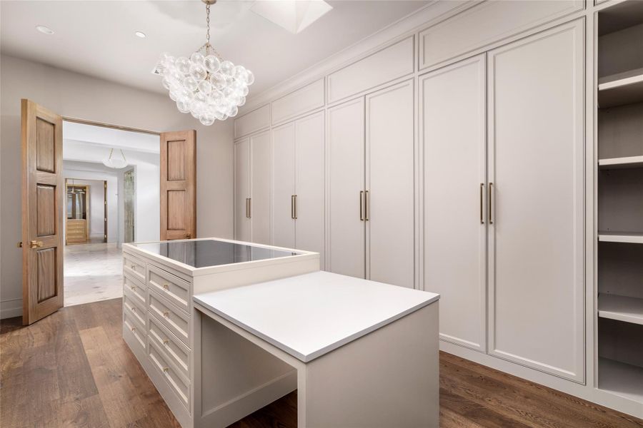 Primary Closet 1 offers a beautifully tailored dressing space with floor-to-ceiling custom cabinetry, abundant concealed storage, and a generous center island with glass-topped display storage. Dedicated illuminated displays for handbags and shoes add a boutique-inspired touch, while white oak flooring and a statement chandelier complete the refined space. Primary Closet 1 offers a beautifully tailored dressing space with floor-to-ceiling custom cabinetry, abundant concealed storage, and a generous center island with glass-topped display storage. Dedicated illuminated displays for handbags and shoes add a boutique-inspired touch, while white oak flooring and a statement chandelier complete the refined space.