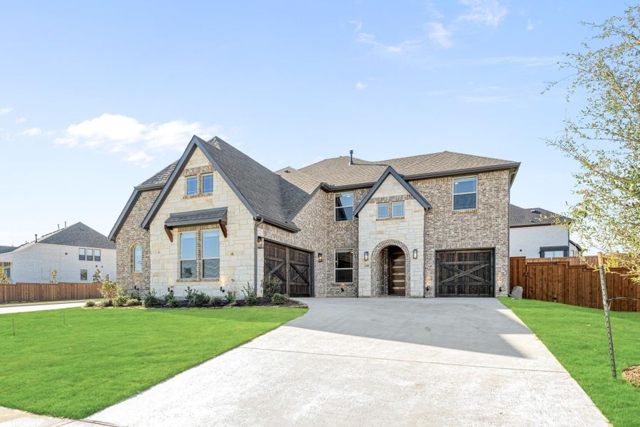 Two-story brick and stone home with two-car garage, arched entry, and manicured front lawn Two-story brick and stone home with two-car garage, arched entry, and manicured front lawn