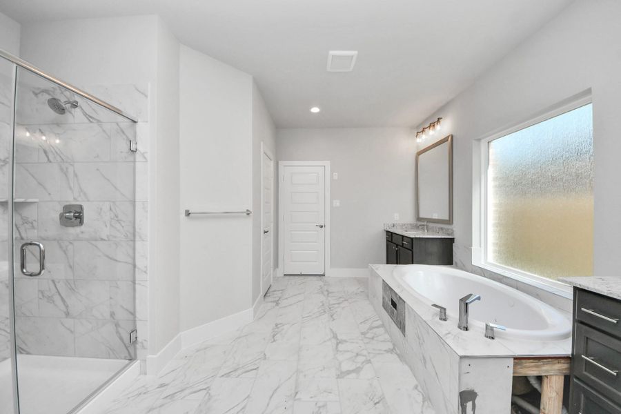 Indulge in a spa-like retreat within the confines of this primary bathroom. Delight in a spacious walk-in shower enveloped in stylish tile surround, unwind in a separate garden tub adorned with custom detailing.