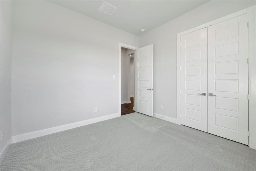 Unfurnished bedroom featuring light carpet and a closet