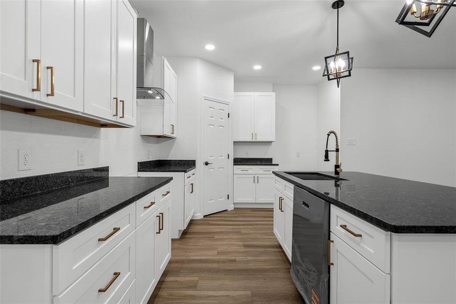 Modern kitchen featuring white shaker cabinetry with brass hardware, dark countertops, and wood-finish flooring Modern kitchen featuring white shaker cabinetry with brass hardware, dark countertops, and wood-finish flooring