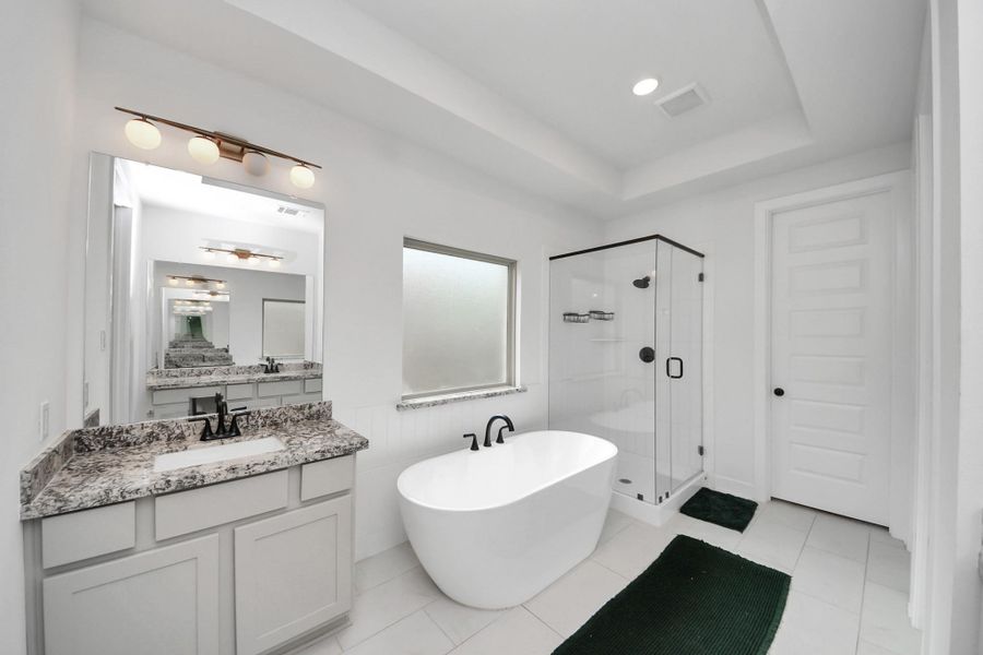 This modern bathroom features a spacious design with a freestanding tub, glass-enclosed shower, and a granite-topped vanity. The neutral color palette and ample lighting create a bright, inviting atmosphere. This modern bathroom features a spacious design with a freestanding tub, glass-enclosed shower, and a granite-topped vanity. The neutral color palette and ample lighting create a bright, inviting atmosphere.