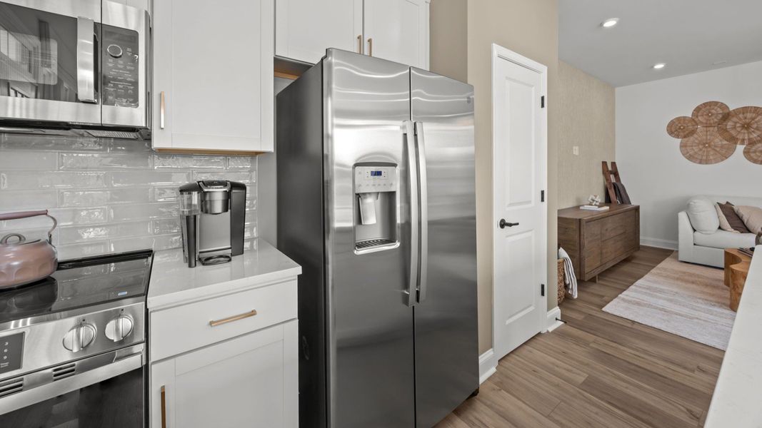 The Rochester Plan by DRB homes kitchen with white cabinets, silver appliances and gold features in Charlotte, NC.