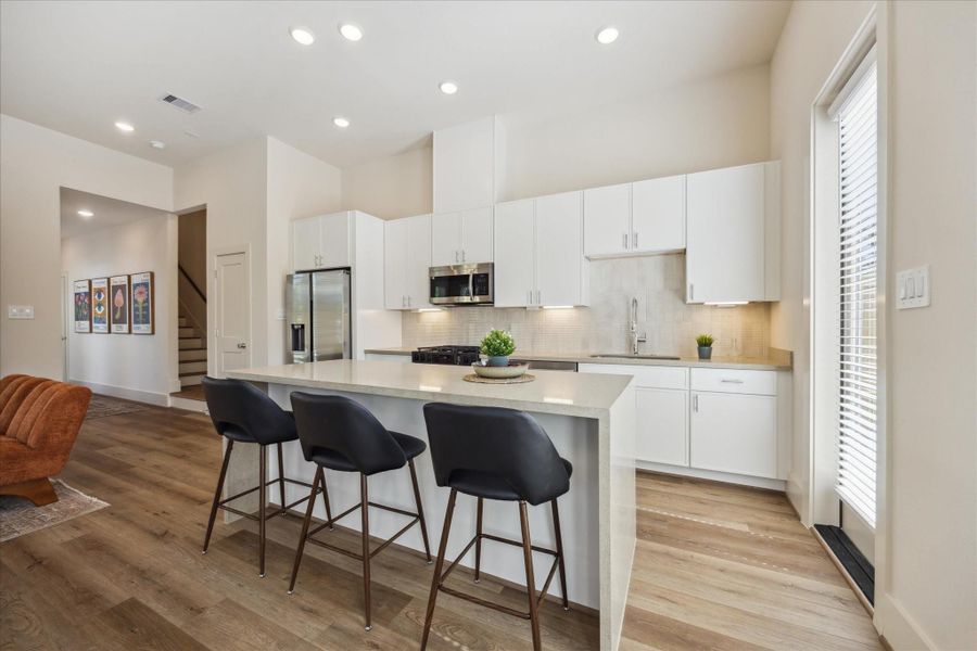 The kitchen is a perfect balance of modern elegance and everyday functionality. Crisp white cabinetry, sleek quartz countertops, and a full suite of stainless steel appliances create a clean, streamlined look.