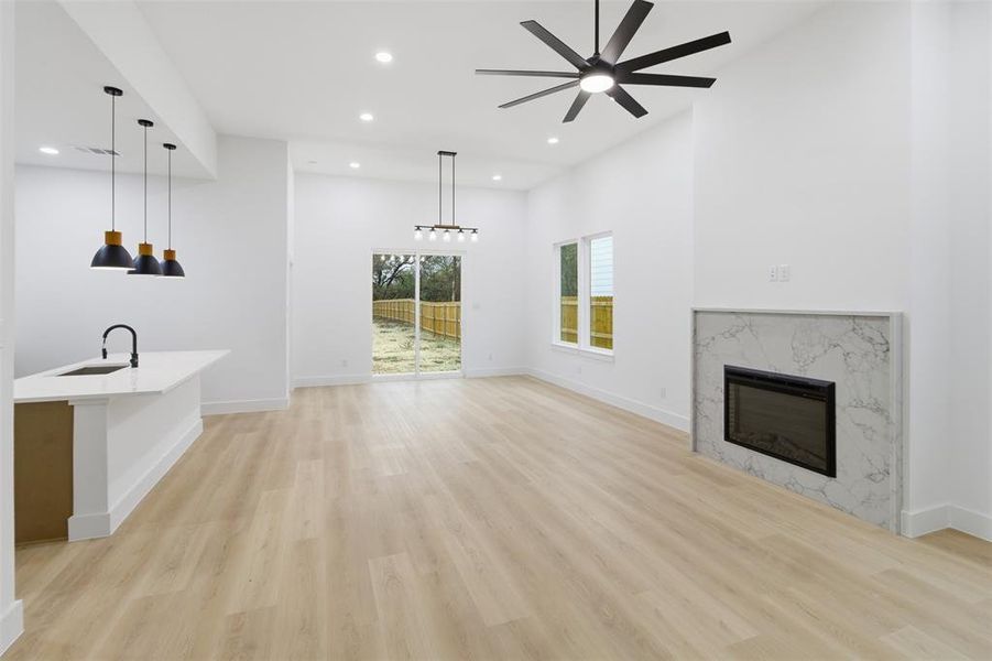 Unfurnished living room featuring a fireplace, light wood finished floors, recessed lighting, and ceiling fan