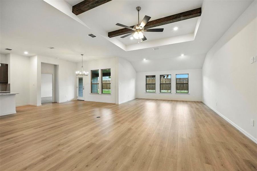 Unfurnished living room featuring recessed lighting, a chandelier, healthy amount of natural light, light wood-style flooring, and beamed ceiling