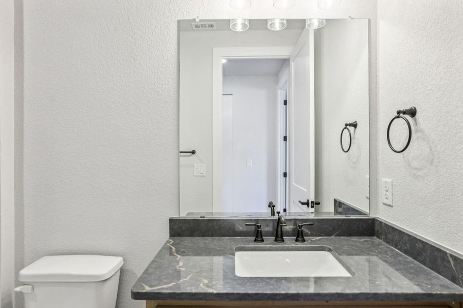 Half bath featuring a textured wall and vanity Half bath featuring a textured wall and vanity