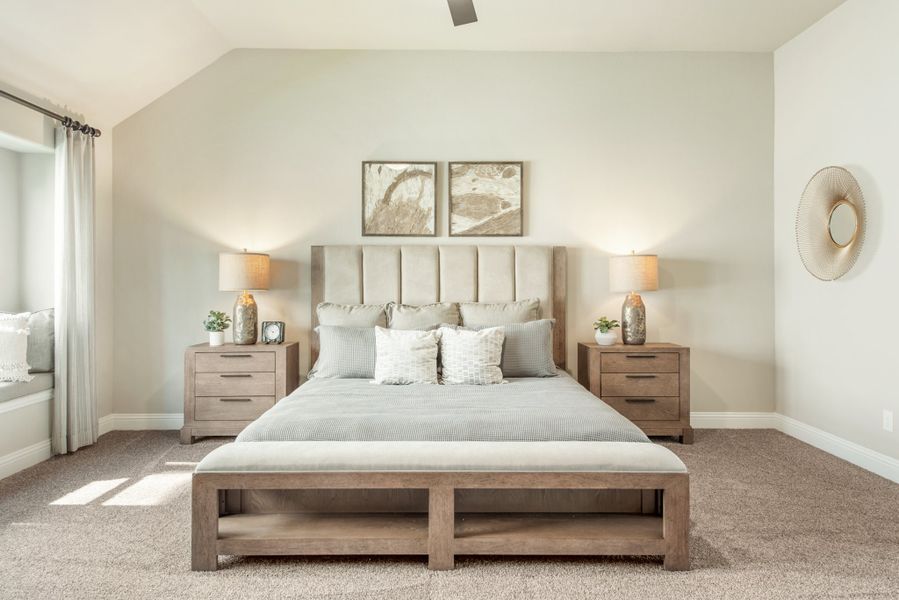 Master bedroom with king bed, vaulted ceiling, wood nightstands, and neutral carpet flooring