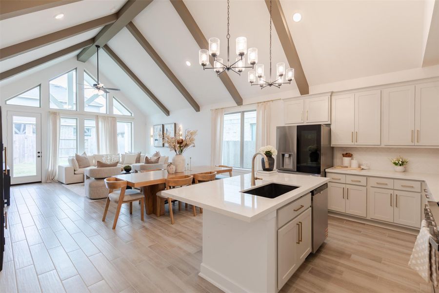 This spacious open-concept kitchen and living area features high vaulted ceilings with wooden beams