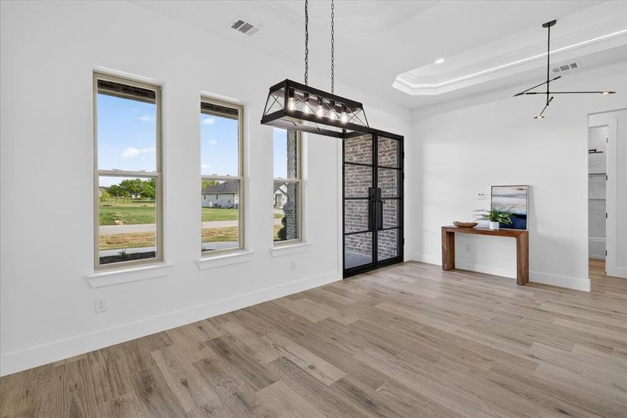 Unfurnished dining area with light wood-style floors and a tray ceiling