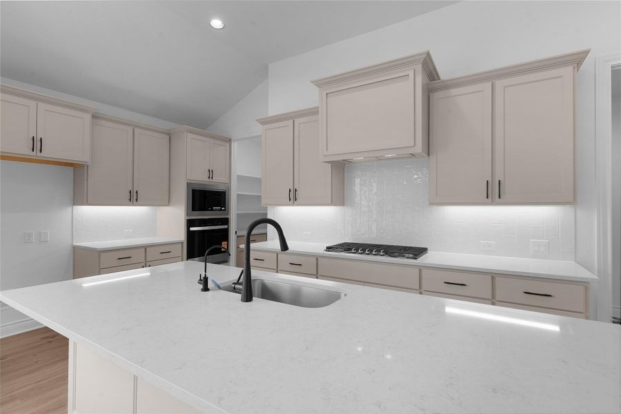 Kitchen featuring light stone counters, cream cabinets, vaulted ceiling, tasteful backsplash, and oven