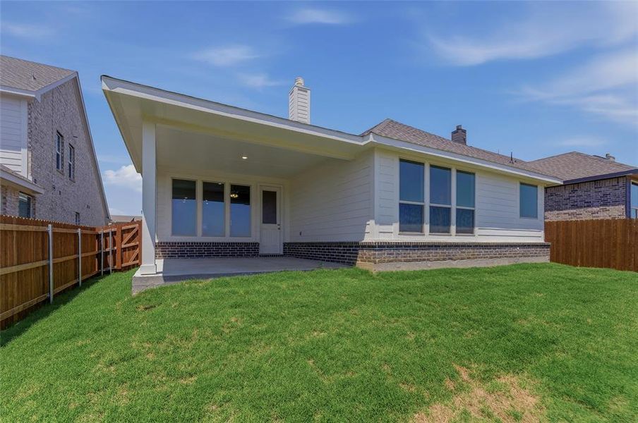 Rear exterior featuring a covered patio, extensive window placements, and a wood privacy fence Rear exterior featuring a covered patio, extensive window placements, and a wood privacy fence
