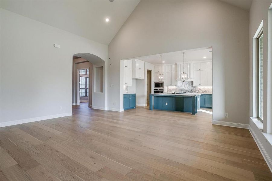 Unfurnished living room with sink, high vaulted ceiling, and light hardwood / wood-style floors