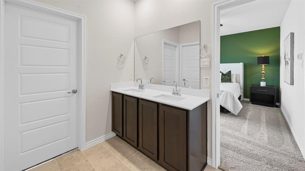 Ensuite bathroom featuring double vanity and baseboards