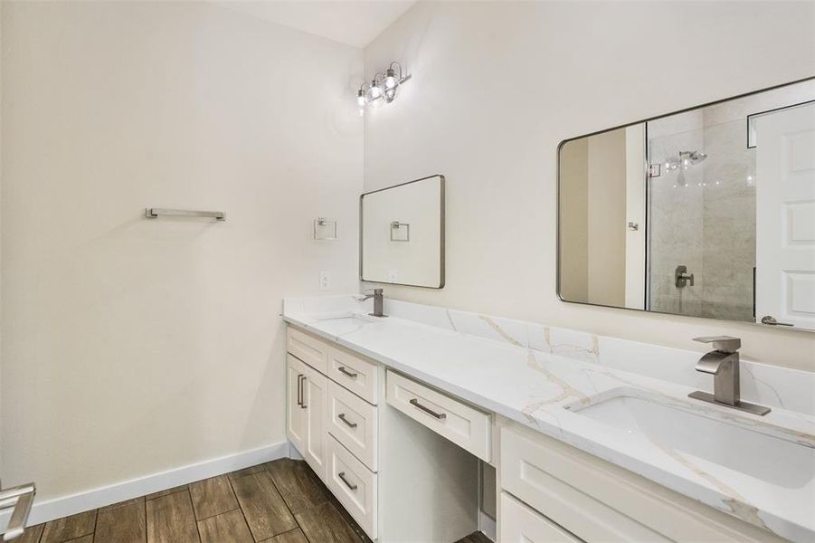 Double vanity featuring white cabinetry, integrated sinks, brushed nickel fixtures, and a white countertop with subtle veining Double vanity featuring white cabinetry, integrated sinks, brushed nickel fixtures, and a white countertop with subtle veining
