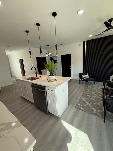 Kitchen with white cabinetry, a kitchen island with sink, dishwasher, pendant lighting, and sink