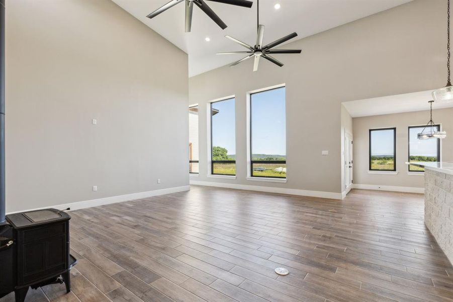Living room featuring high vaulted ceiling, baseboards, wood look tile floors, and ceiling fans. Living room featuring high vaulted ceiling, baseboards, wood look tile floors, and ceiling fans.