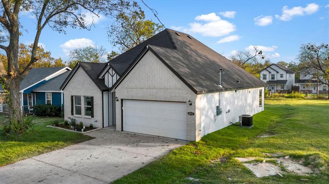 View of front of house featuring cooling unit, a front lawn, and a garage