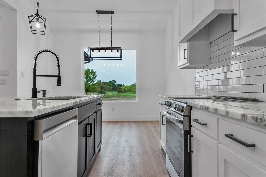 Kitchen with light stone counters, white cabinetry, and stainless steel electric range