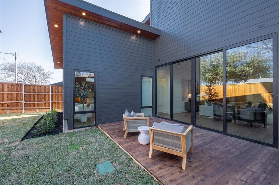 Rear view of property featuring a wooden deck, a lawn, and outdoor lounge area