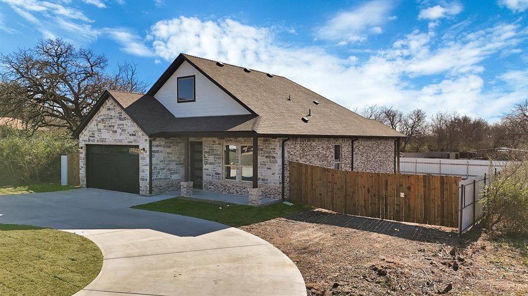 View of front of home with driveway, a shingled roof, an attached garage, and brick siding