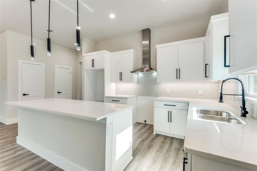 Kitchen featuring backsplash, wall chimney exhaust hood, light hardwood / wood-style floors, and a kitchen island