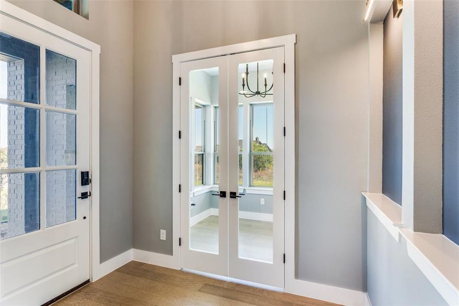 Doorway to outside with french doors, wood finished floors, and a chandelier Doorway to outside with french doors, wood finished floors, and a chandelier