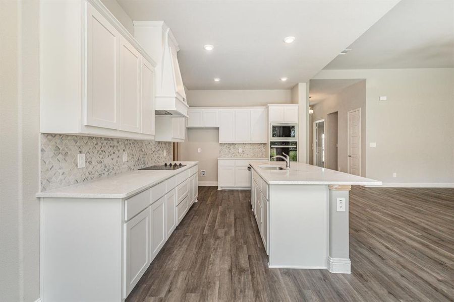 Kitchen featuring decorative backsplash, dark wood-style floors, white cabinetry, recessed lighting, and light stone countertops Kitchen featuring decorative backsplash, dark wood-style floors, white cabinetry, recessed lighting, and light stone countertops