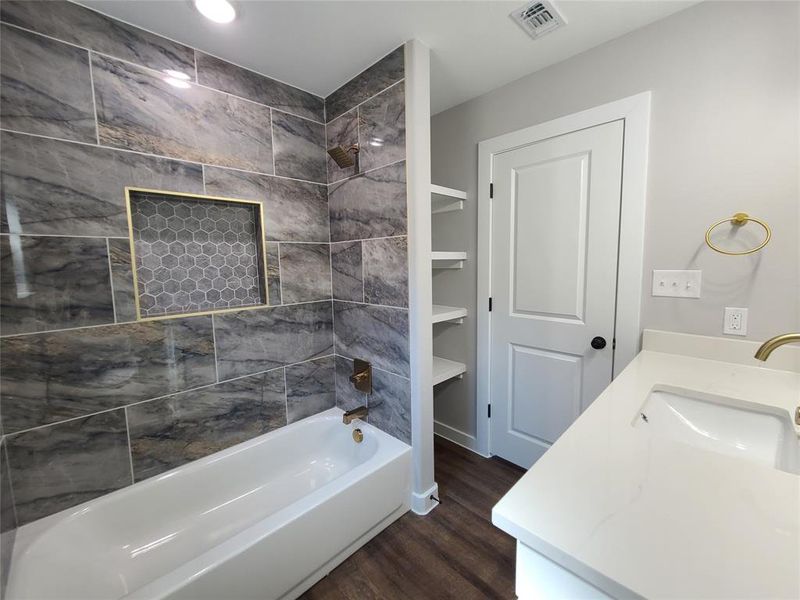 Bathroom featuring tiled shower / bath combo, hardwood / wood-style flooring, and vanity