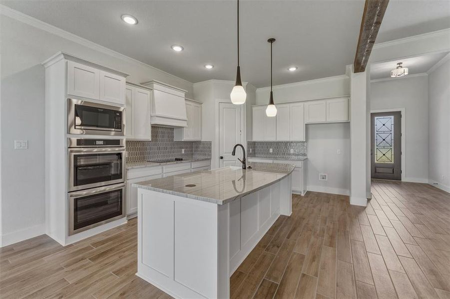 Kitchen featuring a large island, stainless steel built-in appliances, recessed lighting, and wood-finish flooring Kitchen featuring a large island, stainless steel built-in appliances, recessed lighting, and wood-finish flooring