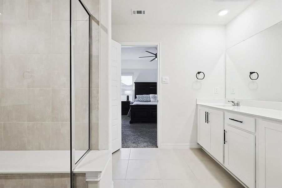 Bathroom with tiled shower, vanity, and tile patterned flooring