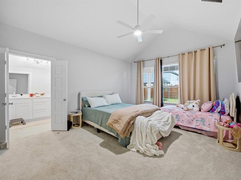 Bedroom featuring carpet, ceiling fan, ensuite bath, and high vaulted ceiling