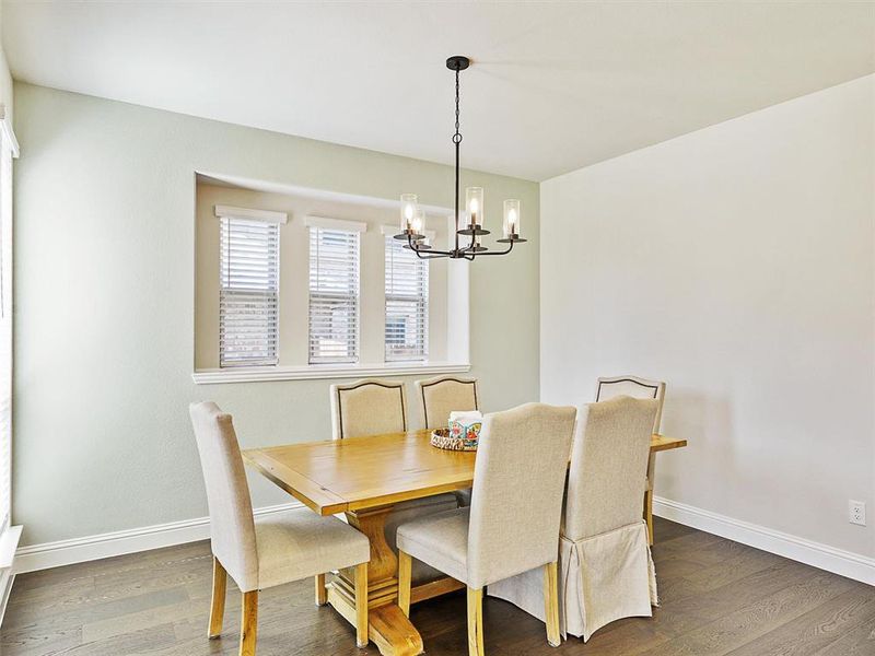 Dining room with dark wood-type flooring and a notable chandelier