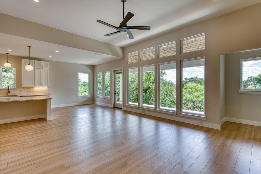 Floor-to-ceiling windows illuminate this open-concept kitchen and living area, offering picturesque outdoor views.