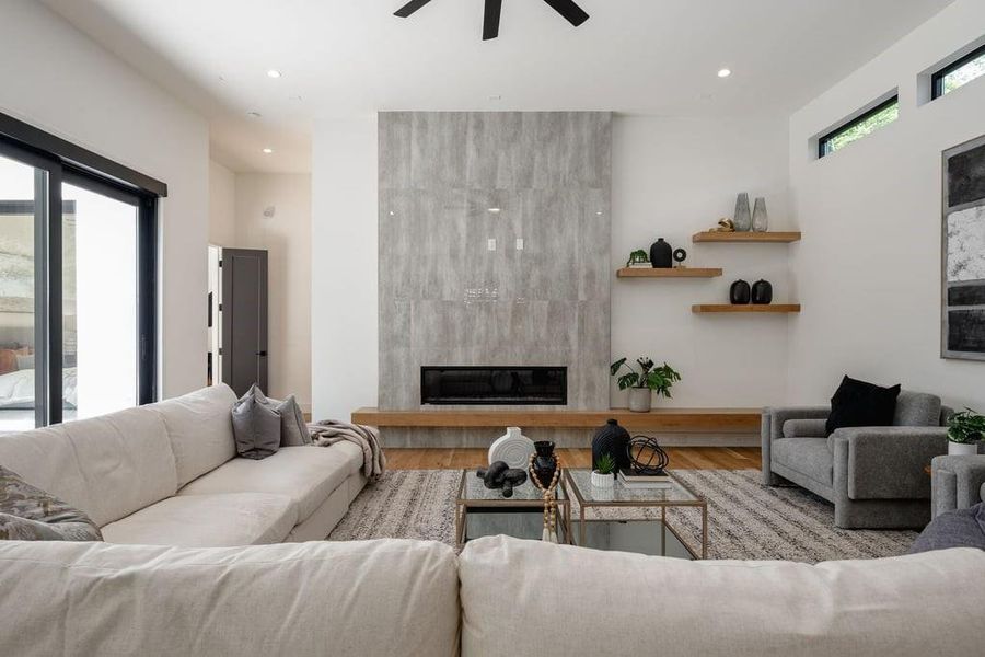 Living room with ceiling fan, light hardwood flooring, a healthy amount of sunlight, and a tile fireplace