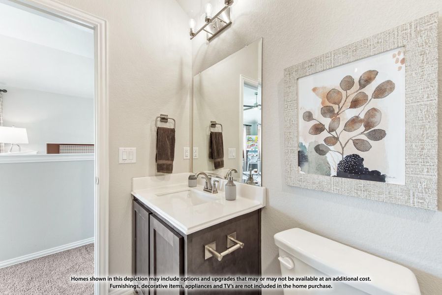 Bathroom with dark wood vanity, white countertop, large mirror, and wall art beside toilet Bathroom with dark wood vanity, white countertop, large mirror, and wall art beside toilet
