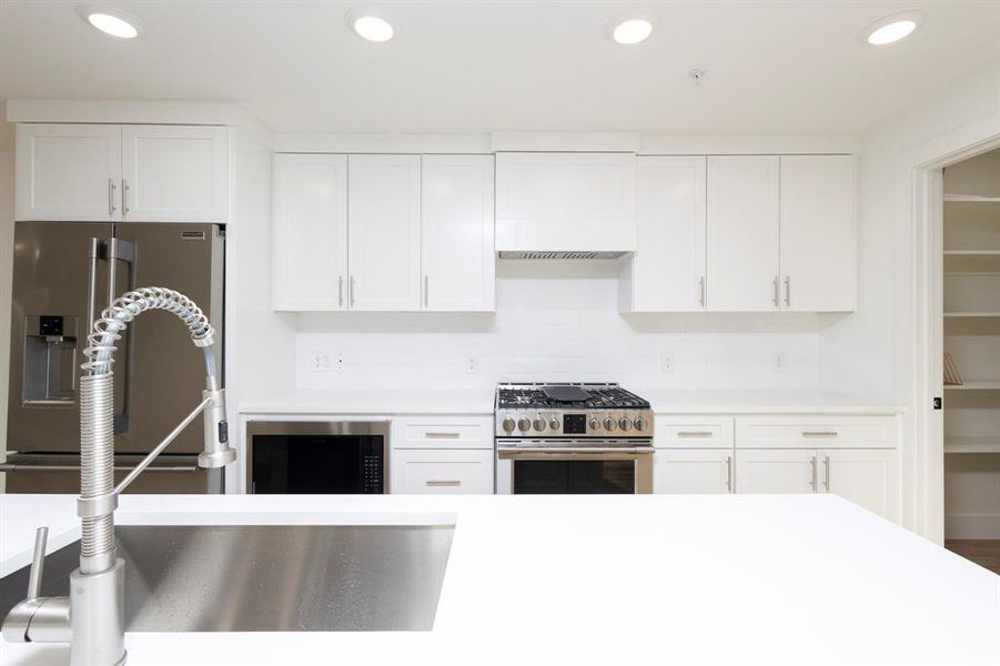 Kitchen featuring appliances with stainless steel finishes, light countertops, white cabinetry, and recessed lighting