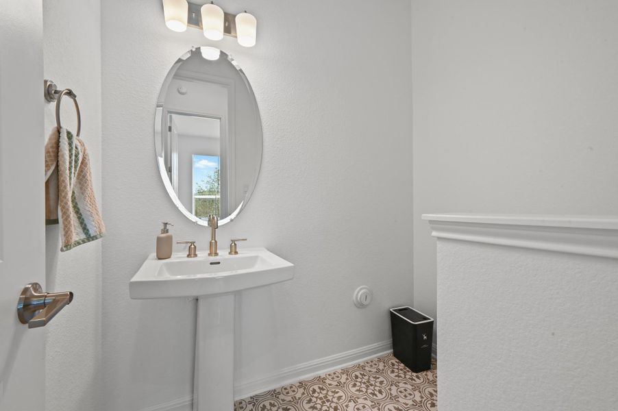 Patterned floor tile pairs with a classic pedestal sink in this elegant powder room.