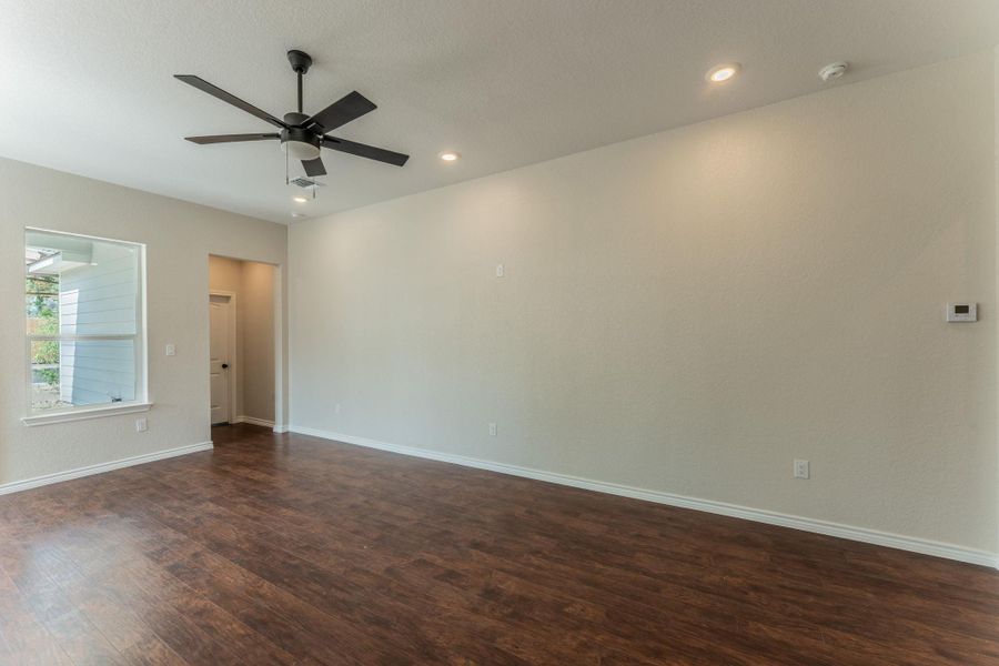 Spacious living area featuring wood-finish flooring, a modern ceiling fan, and recessed lighting
