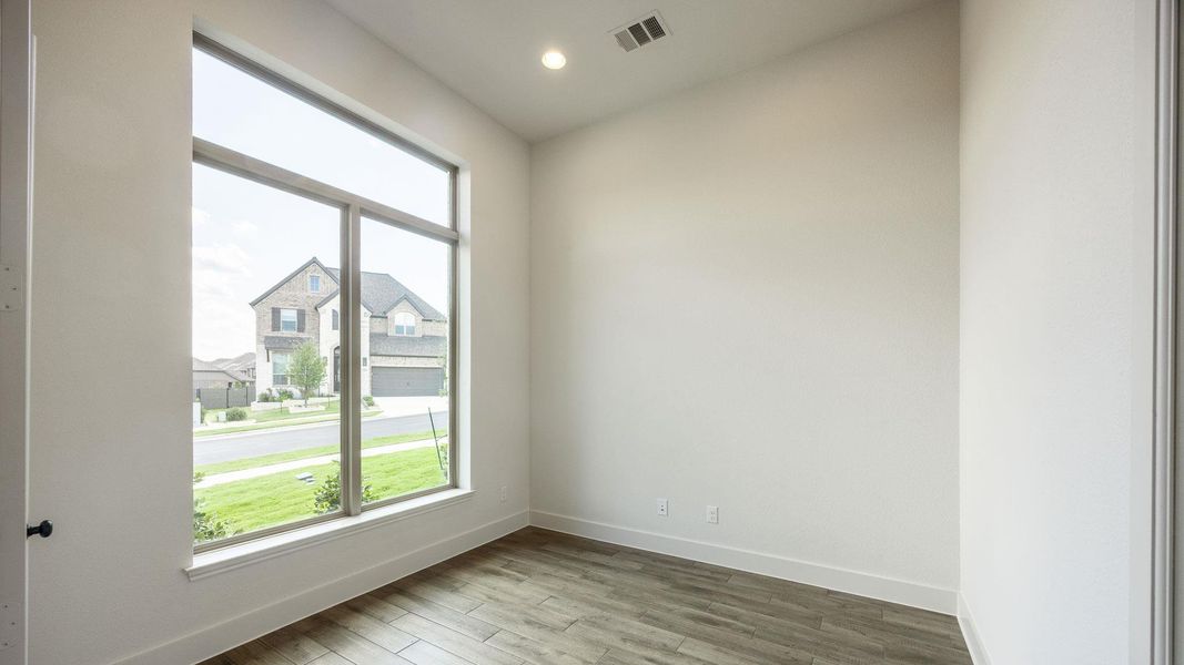 Empty room featuring wood finished floors, recessed lighting, and a residential view Empty room featuring wood finished floors, recessed lighting, and a residential view