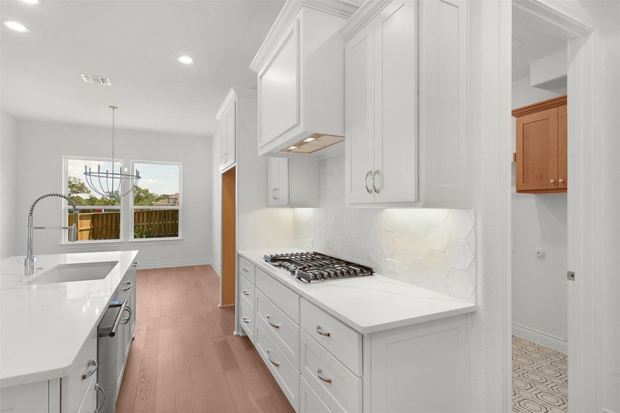 Modern kitchen featuring white cabinetry, light countertops, a gas cooktop, and a hexagonal tile backsplash