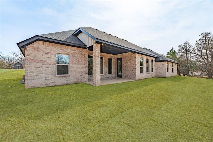 Back of house featuring brick siding, a yard, a patio area, and a shingled roof Back of house featuring brick siding, a yard, a patio area, and a shingled roof