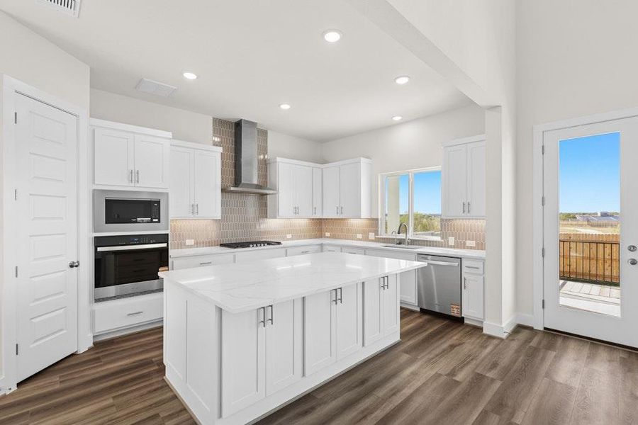 Kitchen featuring white cabinetry, stainless steel appliances, tasteful backsplash, light stone counters, and a center island Kitchen featuring white cabinetry, stainless steel appliances, tasteful backsplash, light stone counters, and a center island